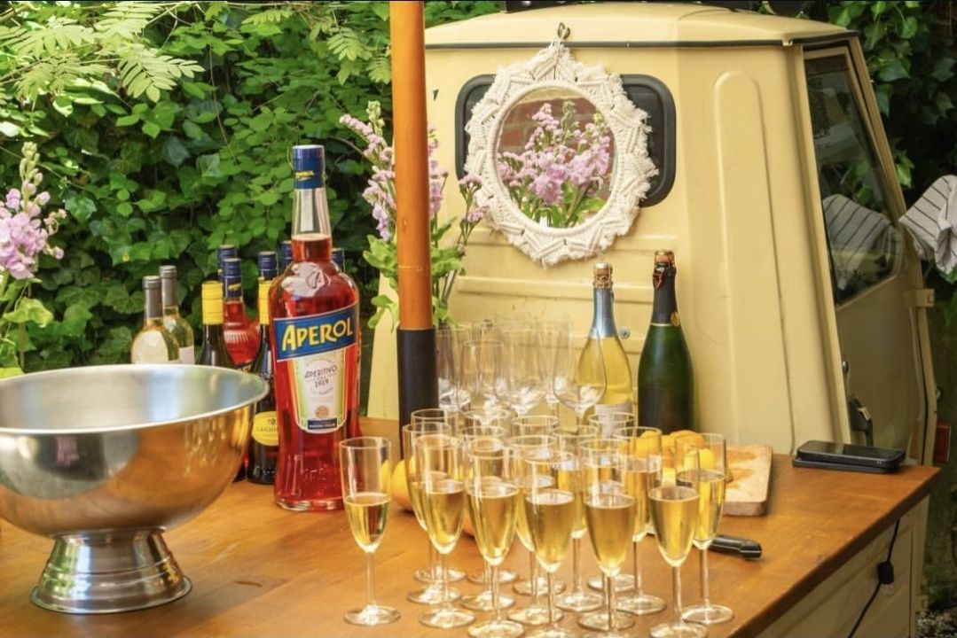 Sektempfang an der Ape-Bar: gefüllte Sektgläser, Aperol und Weinflaschen auf der Holztheke