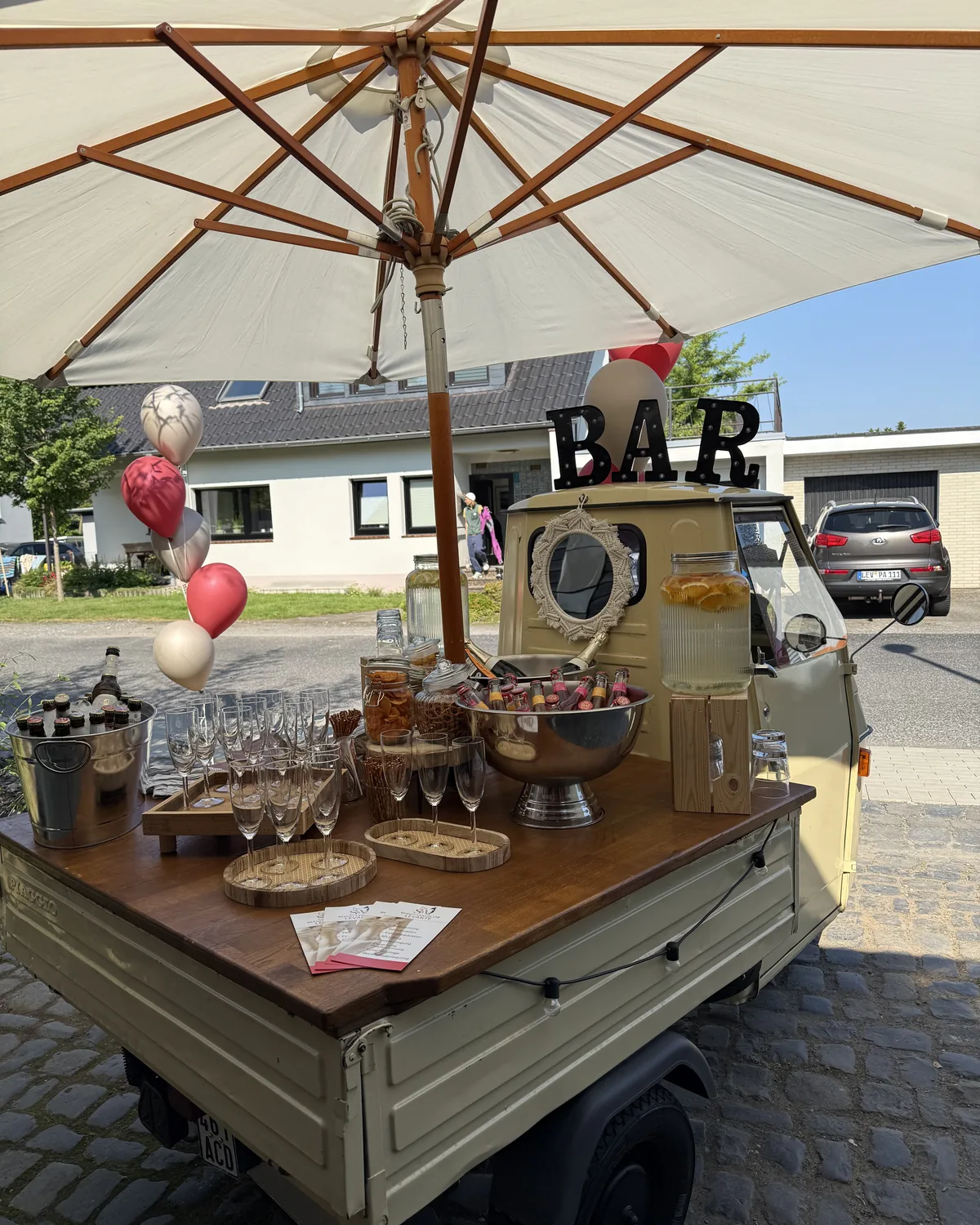 Festlich dekorierte Theke der Ape-Bar mit Sektgläsern und Ballons bei einer Eröffnungsfeier in Leverkusen