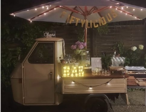 Livape bei Nacht: leuchtender BAR-Schriftzug und Lichterkette am Schirm der Piaggio Ape